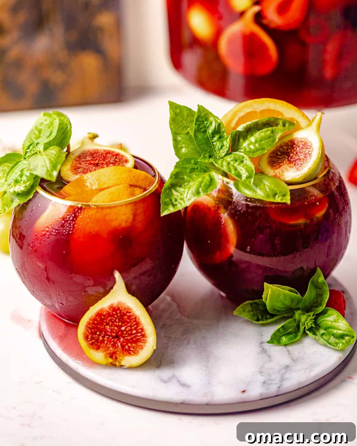 Two elegant glasses of bourbon sangria, artfully garnished with fresh figs and fragrant basil, ready for a toast.