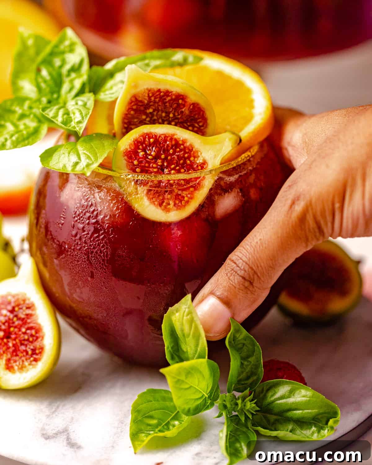 A hand gracefully holding a wine glass filled with luscious bourbon sangria, ready for a sip.