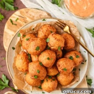 Golden-brown, perfectly fried Southern Sweet Onion Hush Puppies piled on a plate.