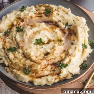 A serving of creamy Brown Butter and Herb Mashed Potatoes, garnished with fresh herbs.