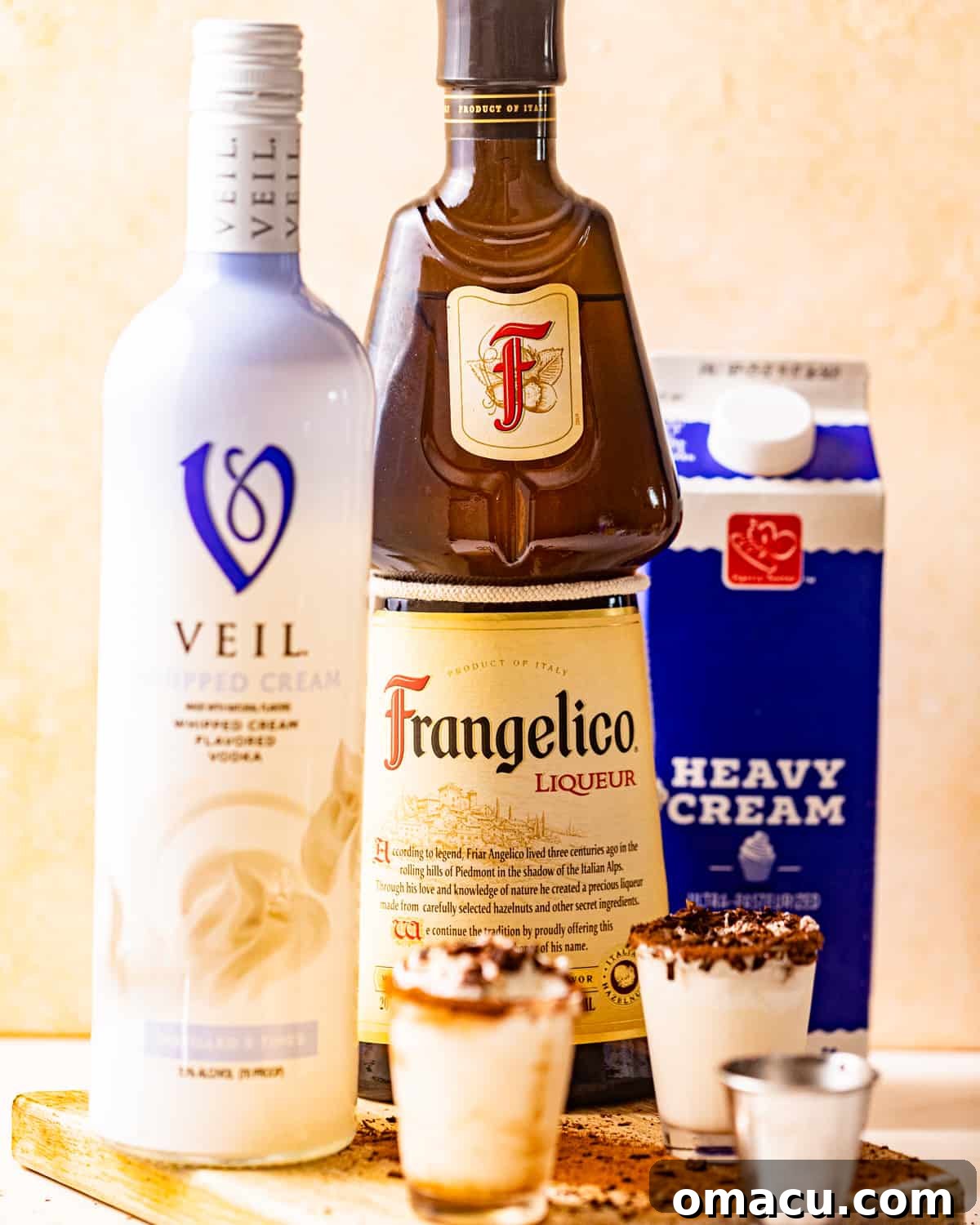 Ingredients laid out for a chocolate cake shot: whipped cream vodka, hazelnut liqueur, and heavy cream.