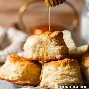 buttermilk biscuits on a plate with honey drizzled on top.
