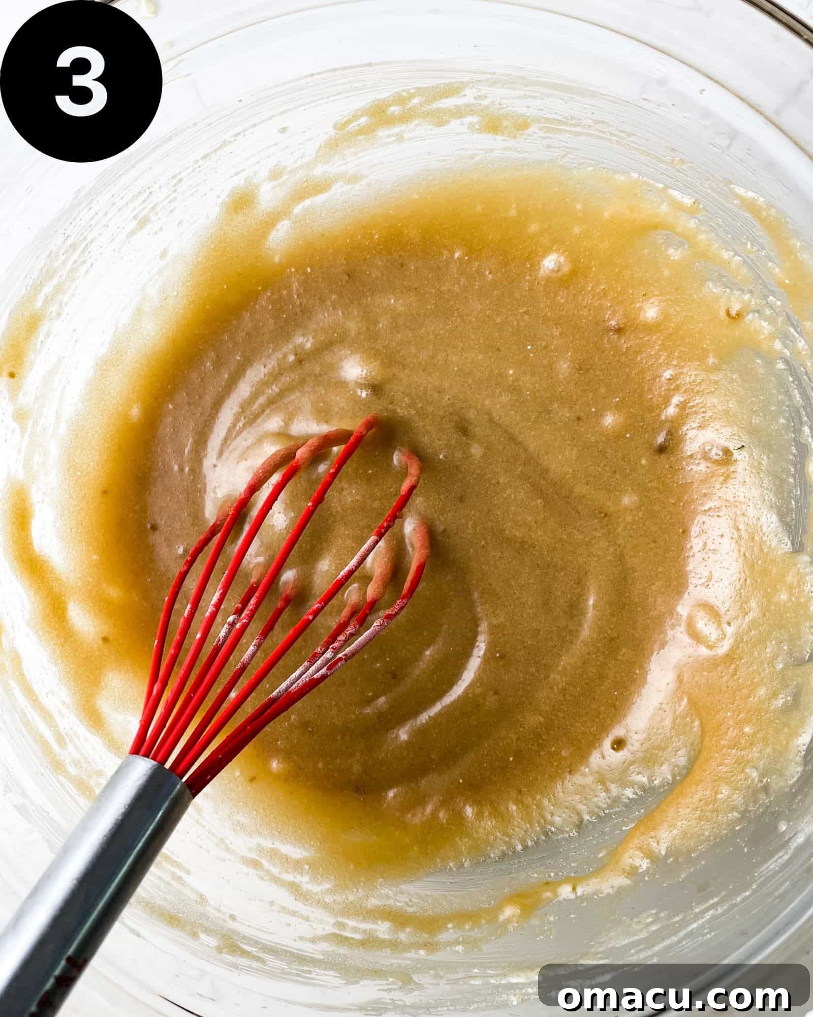 A bowl of wet ingredients, including sugars, oil, and sour cream, smoothly whisked together.