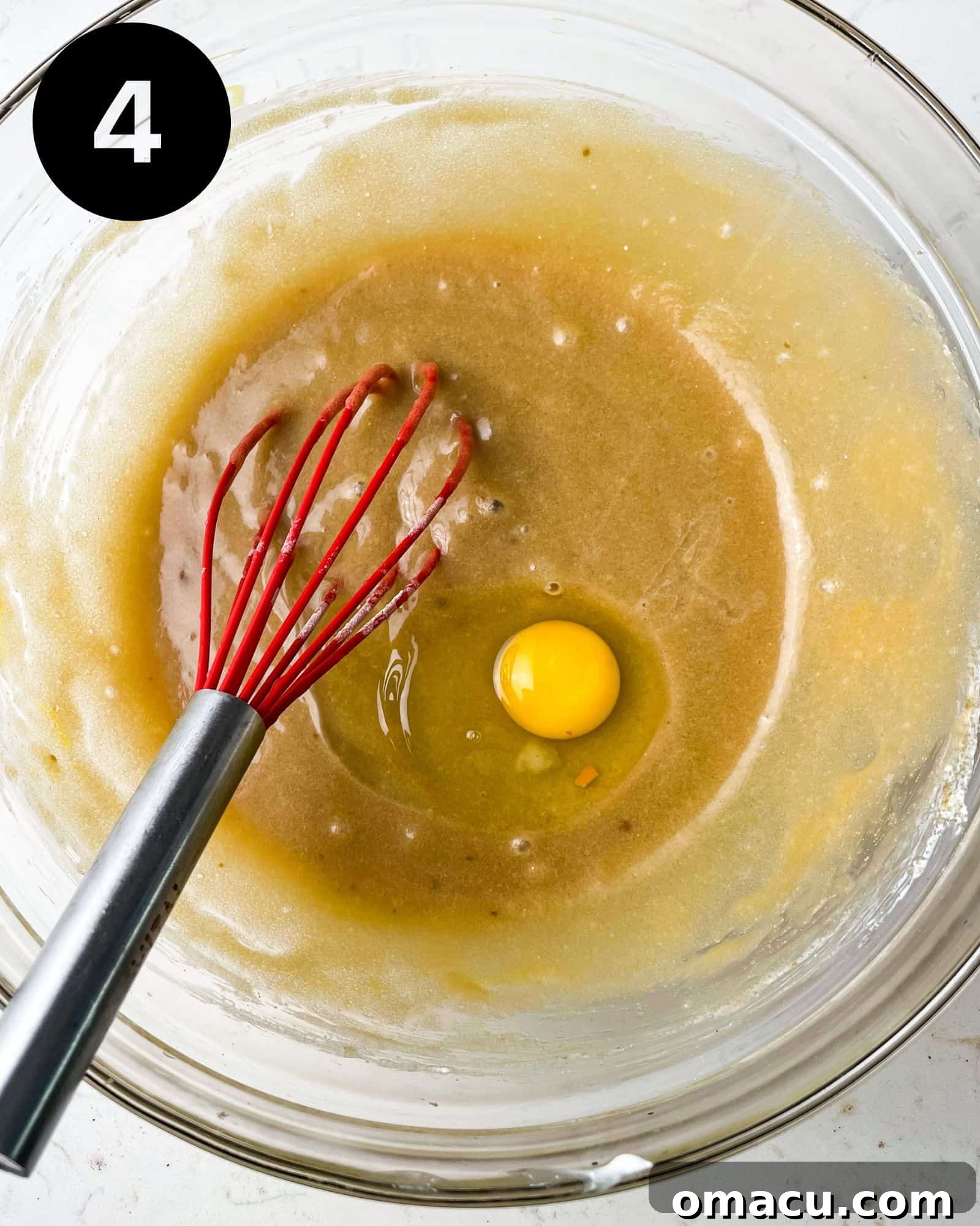 A large egg being cracked into the bowl of wet ingredients, ready to be whisked.