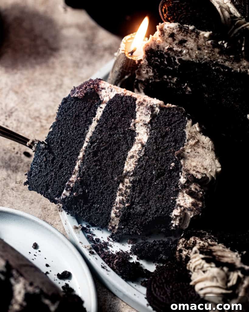 A delectable slice of Black Velvet Cake, showing the dark layers of cake and thick white Oreo cream cheese frosting, resting on a cake server.