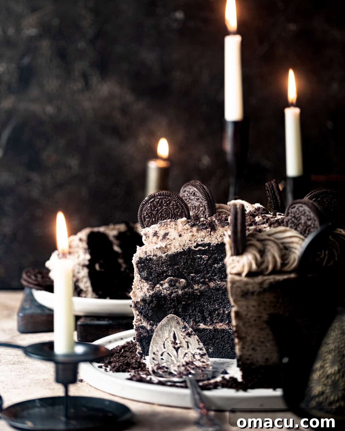 A beautifully frosted black velvet cake on a large decorative plate, garnished with whole and crushed Oreo cookies, ready to be served.