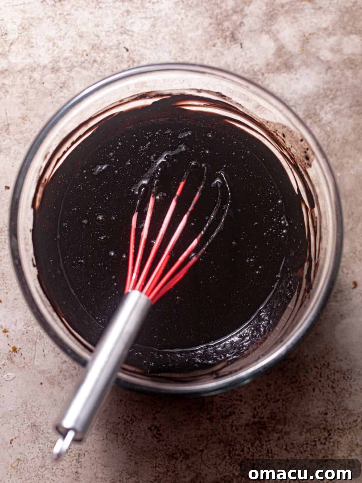 Hot coffee being carefully poured into the cake batter, which is then gently mixed to incorporate.
