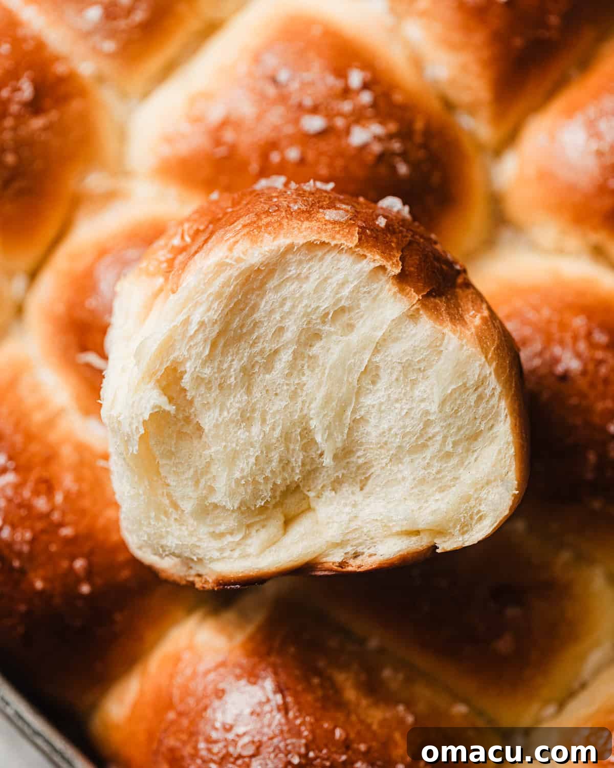 Stacked brioche dinner rolls showcasing their fluffy interior, highlighting their soft texture and golden-brown crust.