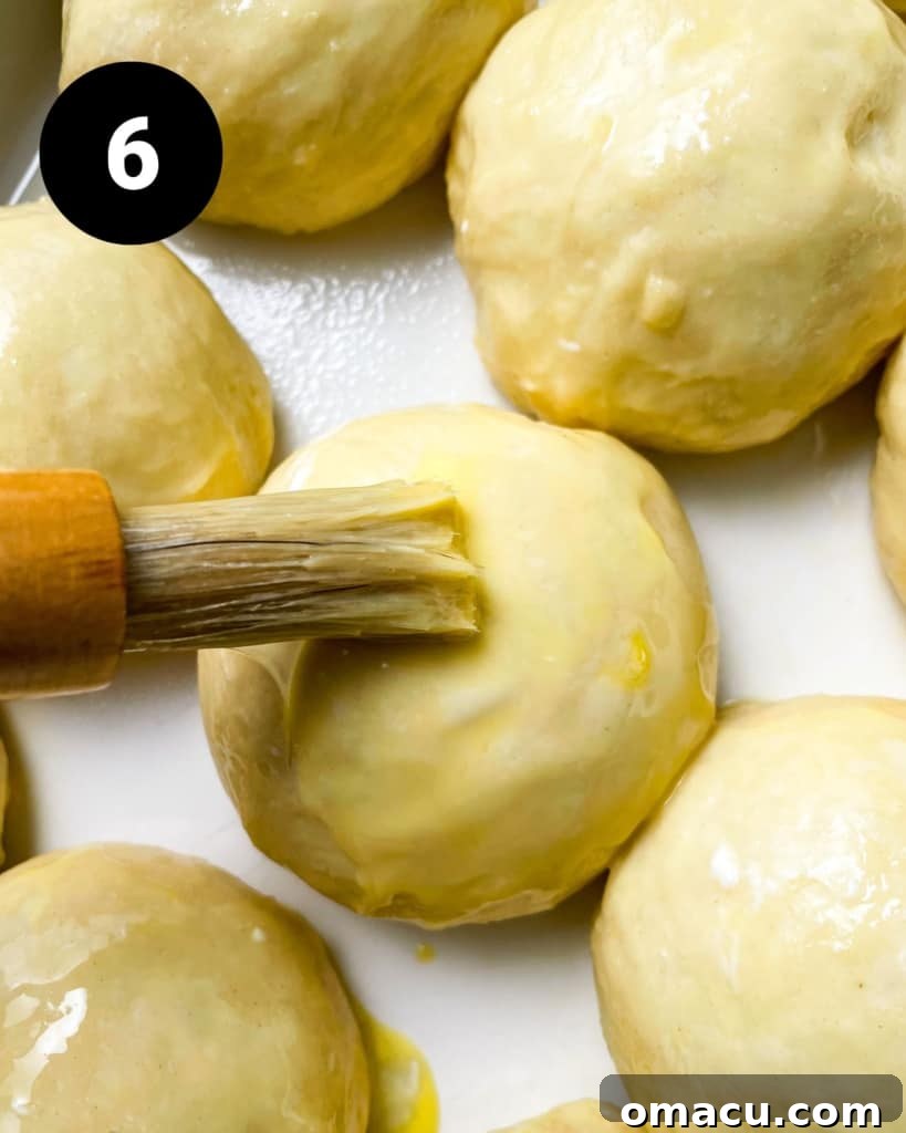 Brioche dough balls being brushed with an egg wash before baking, for a golden finish.