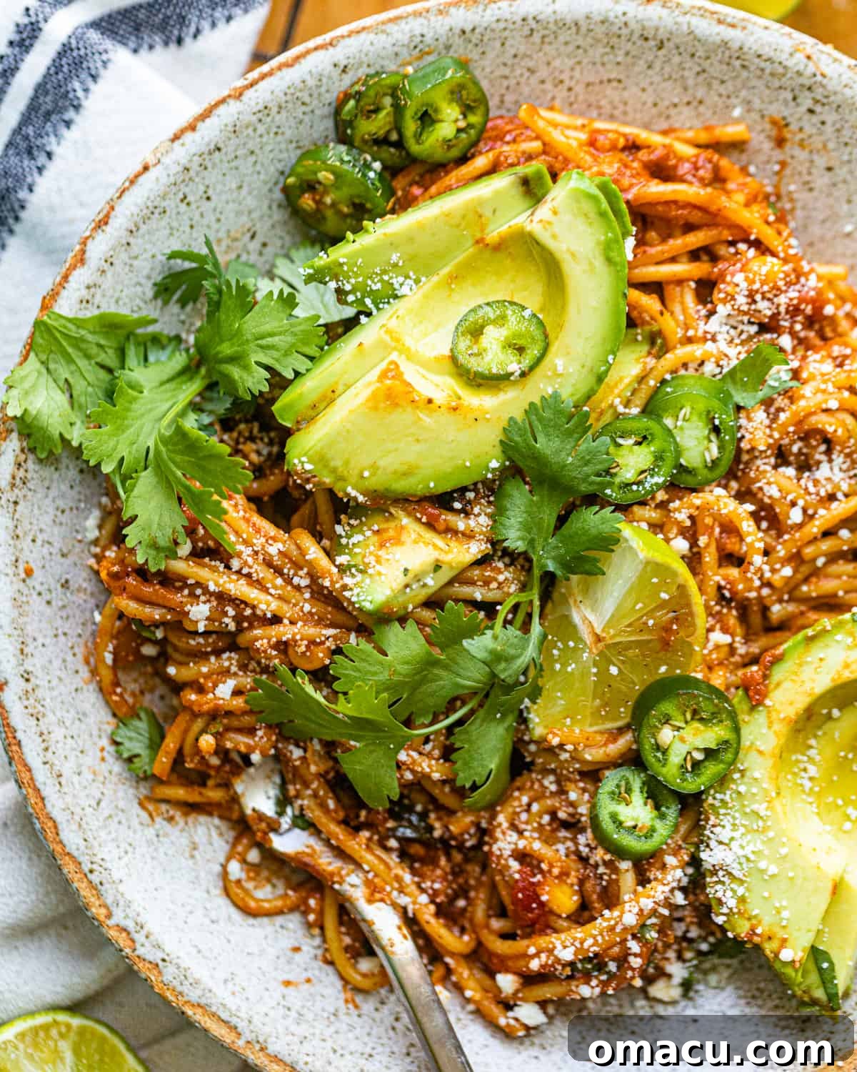 A plate of delicious taco pasta topped with fresh avocado slices.