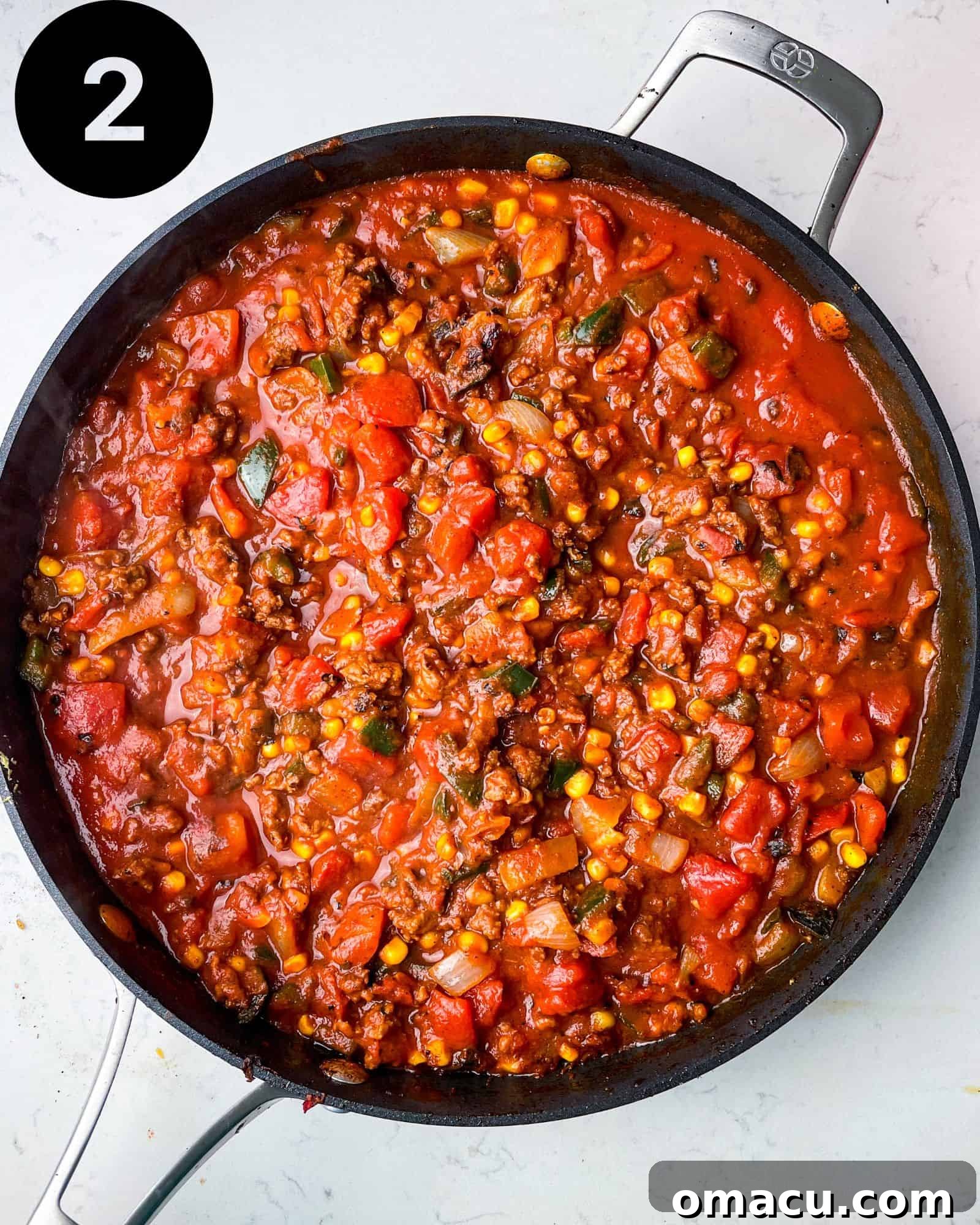 The rich, red spaghetti sauce simmering in a large pan, infused with Mexican spices and vegetables.