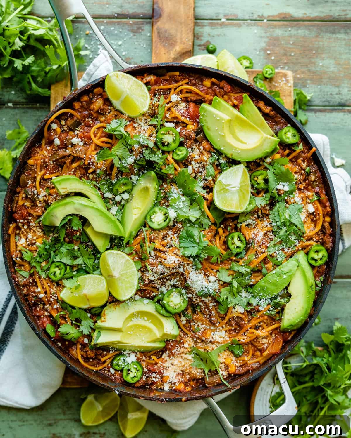 A large skillet filled with one pot taco spaghetti, garnished and ready for serving.