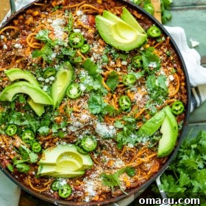Mexican spaghetti in a large skillet garnished with cotija, avocado, and cilantro.
