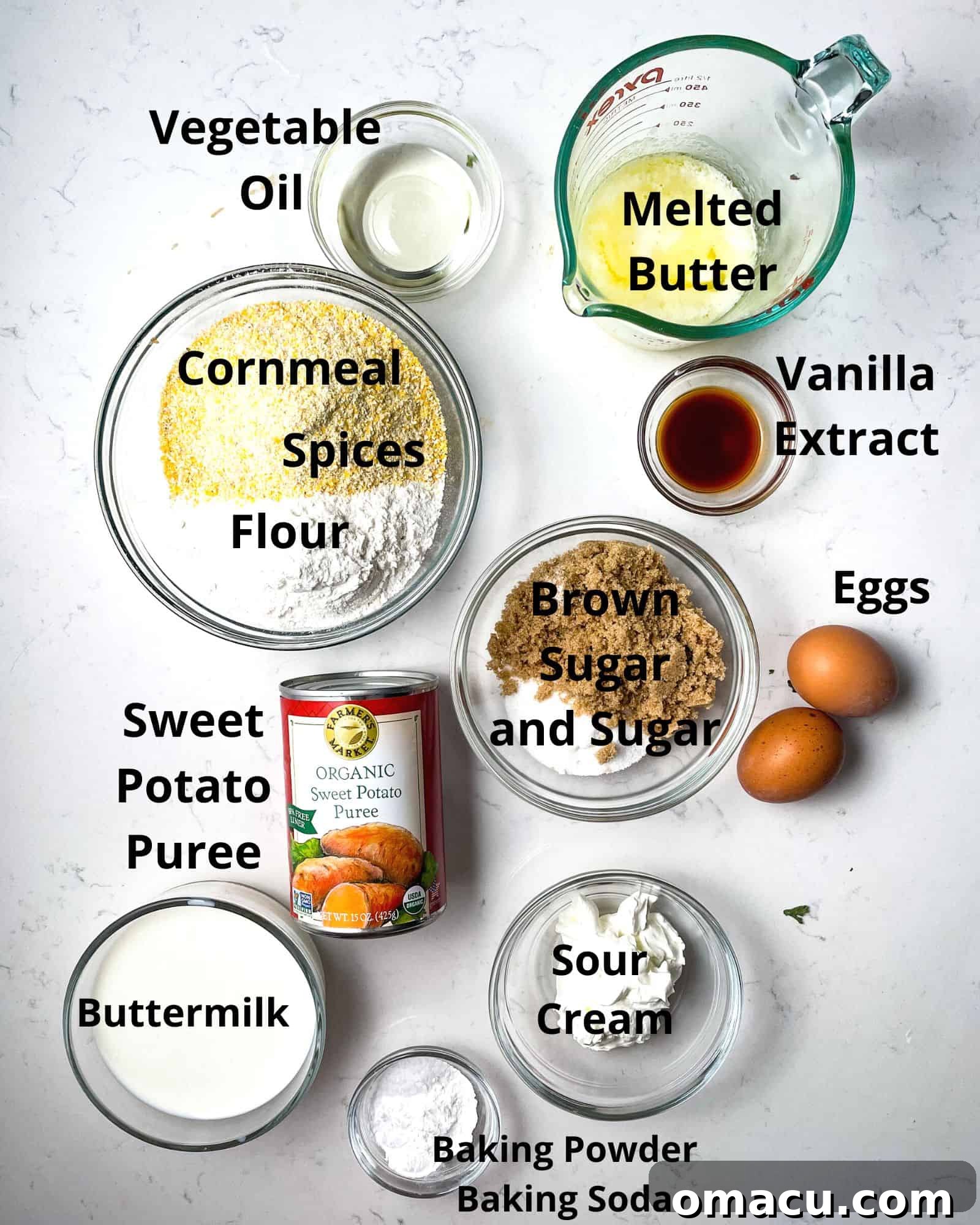 ingredients to make sweet potato cornbread - flour, cornmeal, spices, brown sugar, sugar, baking soda, baking powder, sour cream, buttermilk, butter, vanilla extract, and eggs displayed.