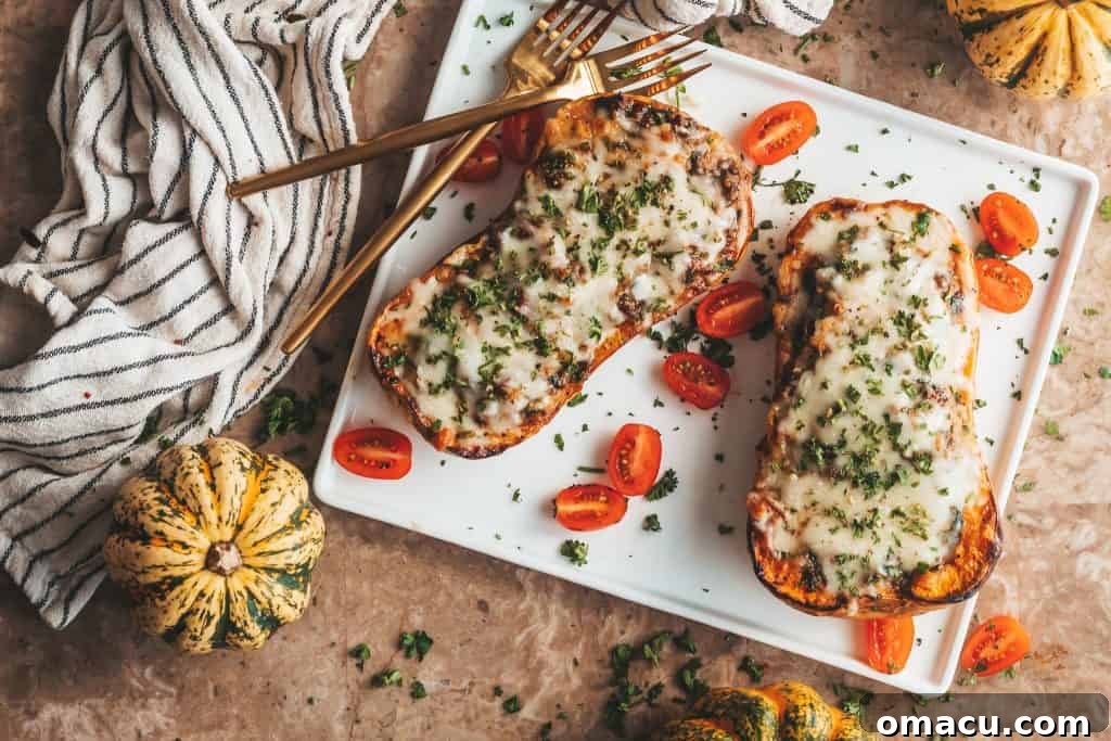 Two halves of loaded butternut squash boats with a savory beef and cheese filling, garnished with fresh parsley.