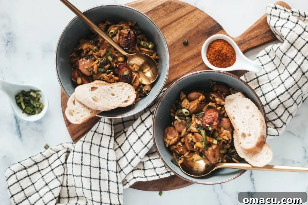 A bowl of summery cajun orzo with kielbasa, garnished with fresh herbs, showcasing a colorful and appetizing dish.