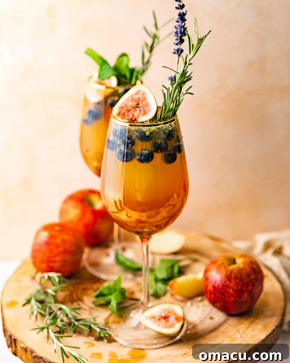 Two glasses of white wine sangria, elegantly arranged on a rustic serving board with additional fruit garnishes.