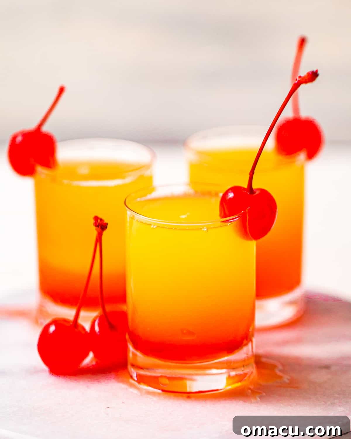 Pineapple Upside Down Cake Shots garnished with maraschino cherries.