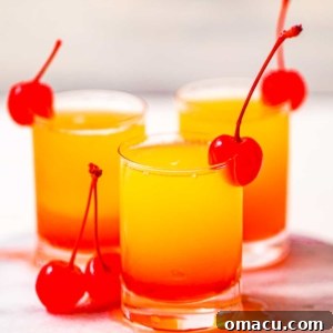 up close photo of pineapple upside down cake shots garnished with maraschino cherries.