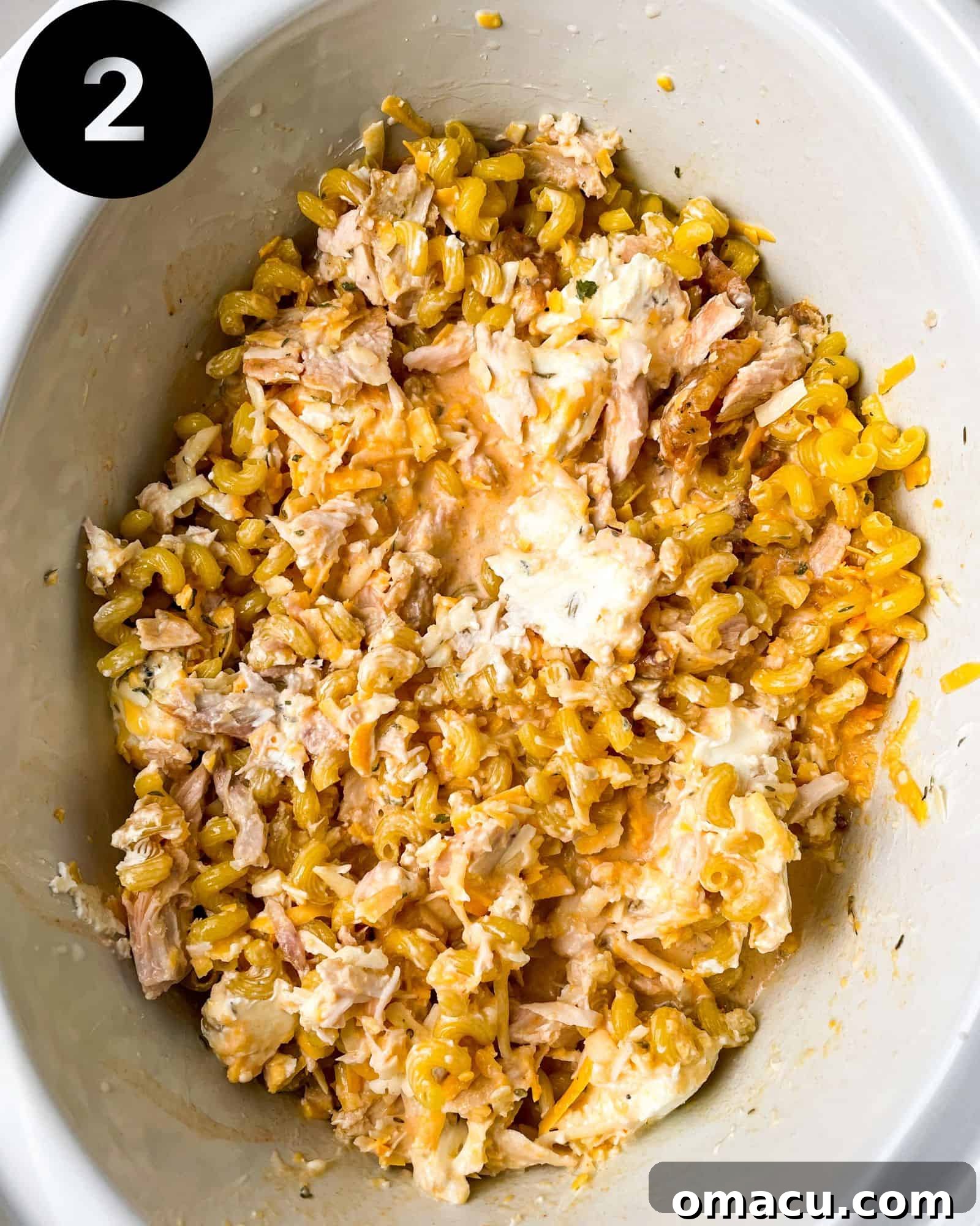 Step 2: Crockpot Buffalo Chicken Mac and Cheese cooking in a slow cooker, with pasta added and sauce thickening.