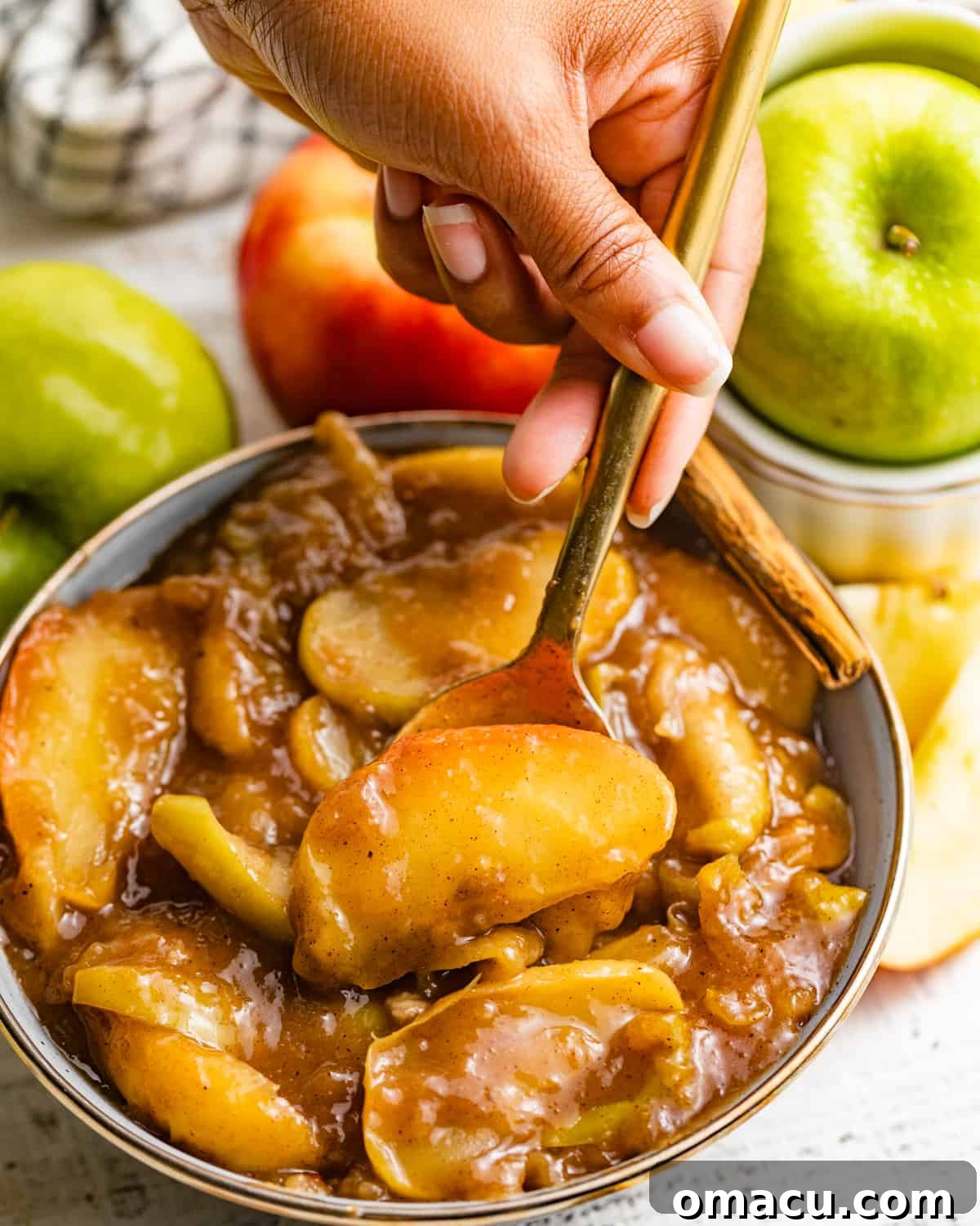 A spoon diving into a bowl of freshly made apple pie filling, ready to be enjoyed.