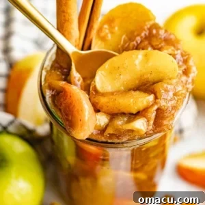 An up-close photo of apple pie filling in a jar with a spoon.