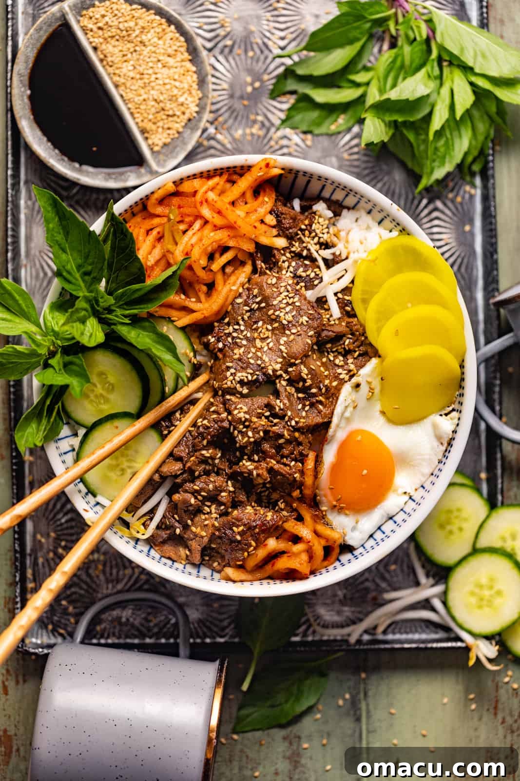 A vibrant Korean Bulgogi bowl featuring tender marinated beef, fluffy white rice, sliced cucumbers, spicy kimchi, and a fried egg, ready to be enjoyed.
