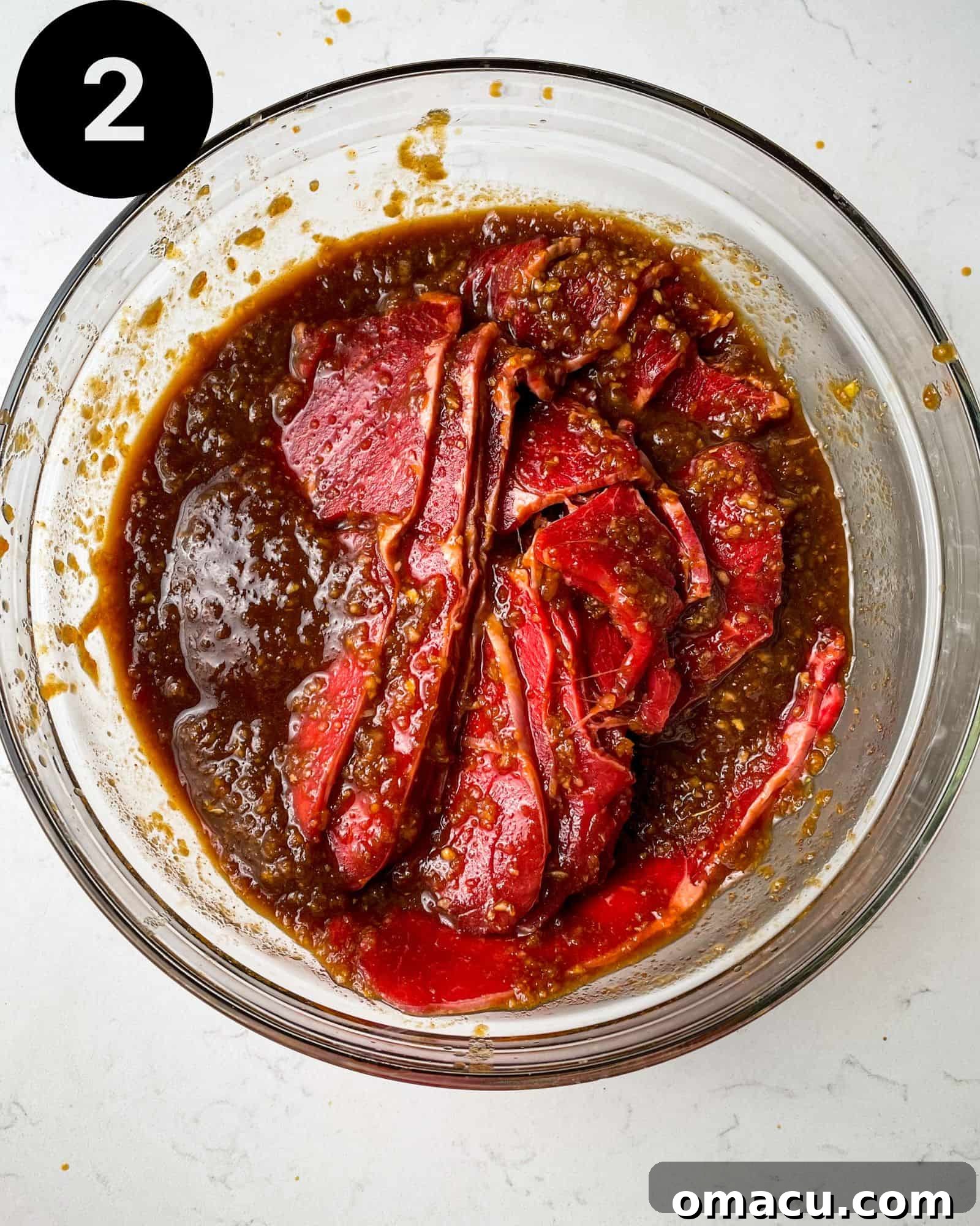 Thinly sliced beef marinating in a flavorful Korean bulgogi sauce within a bowl, ready for cooking.