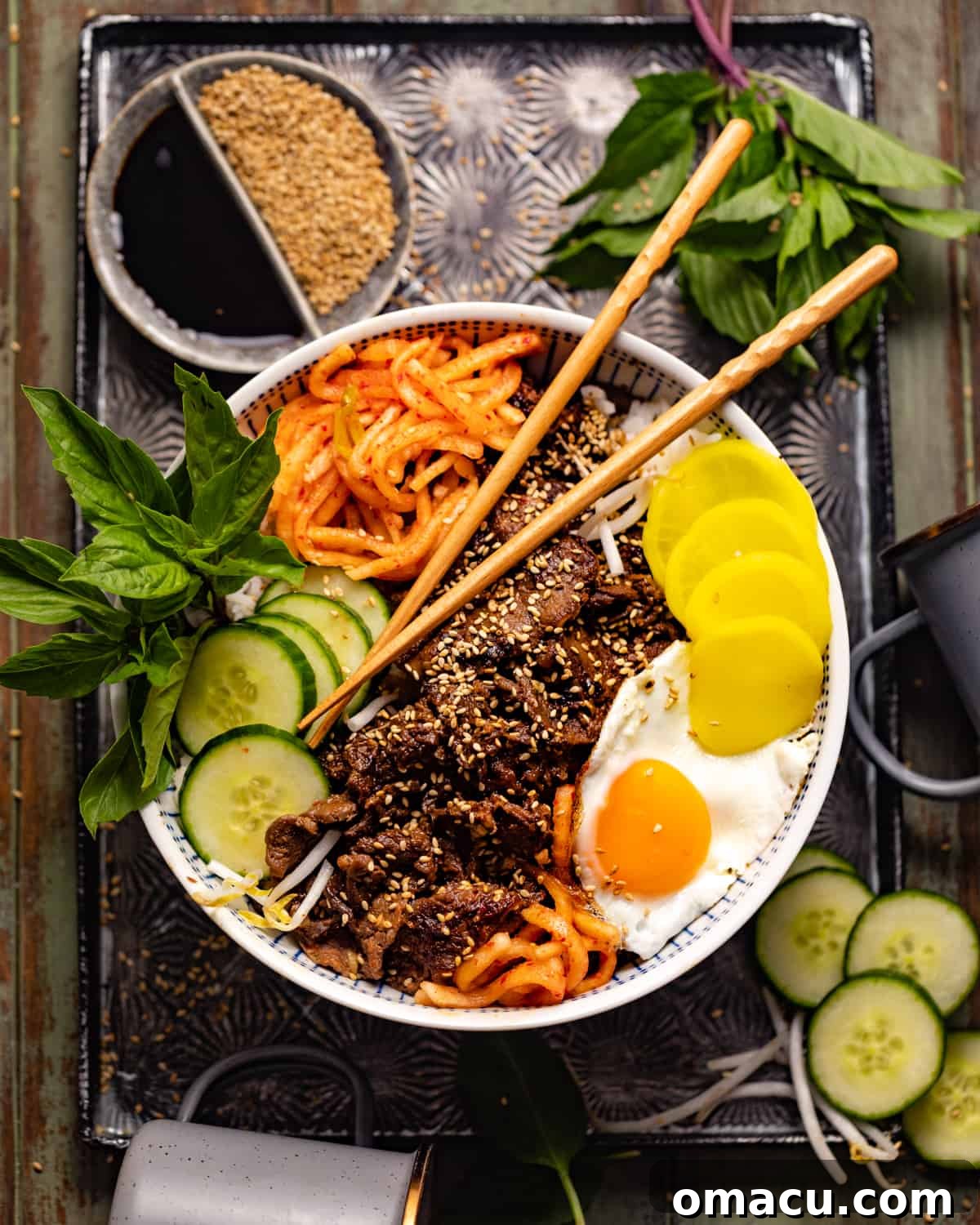 A finished Bulgogi bowl, complete with rice, beef, an egg, and vegetables, presented on a serving tray with chopsticks.