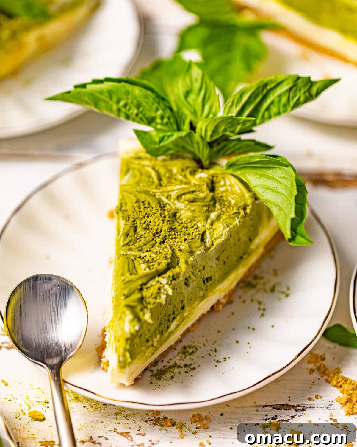 A beautifully sliced piece of green tea cheesecake on a white plate, ready to be enjoyed.