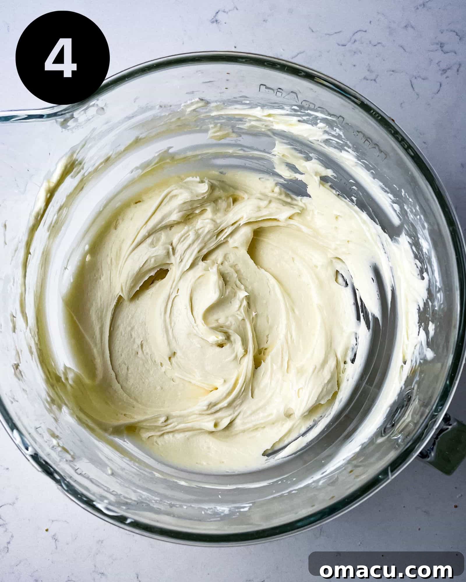 The fluffy, smooth cream cheese and powdered sugar mixture in a stand mixer bowl.