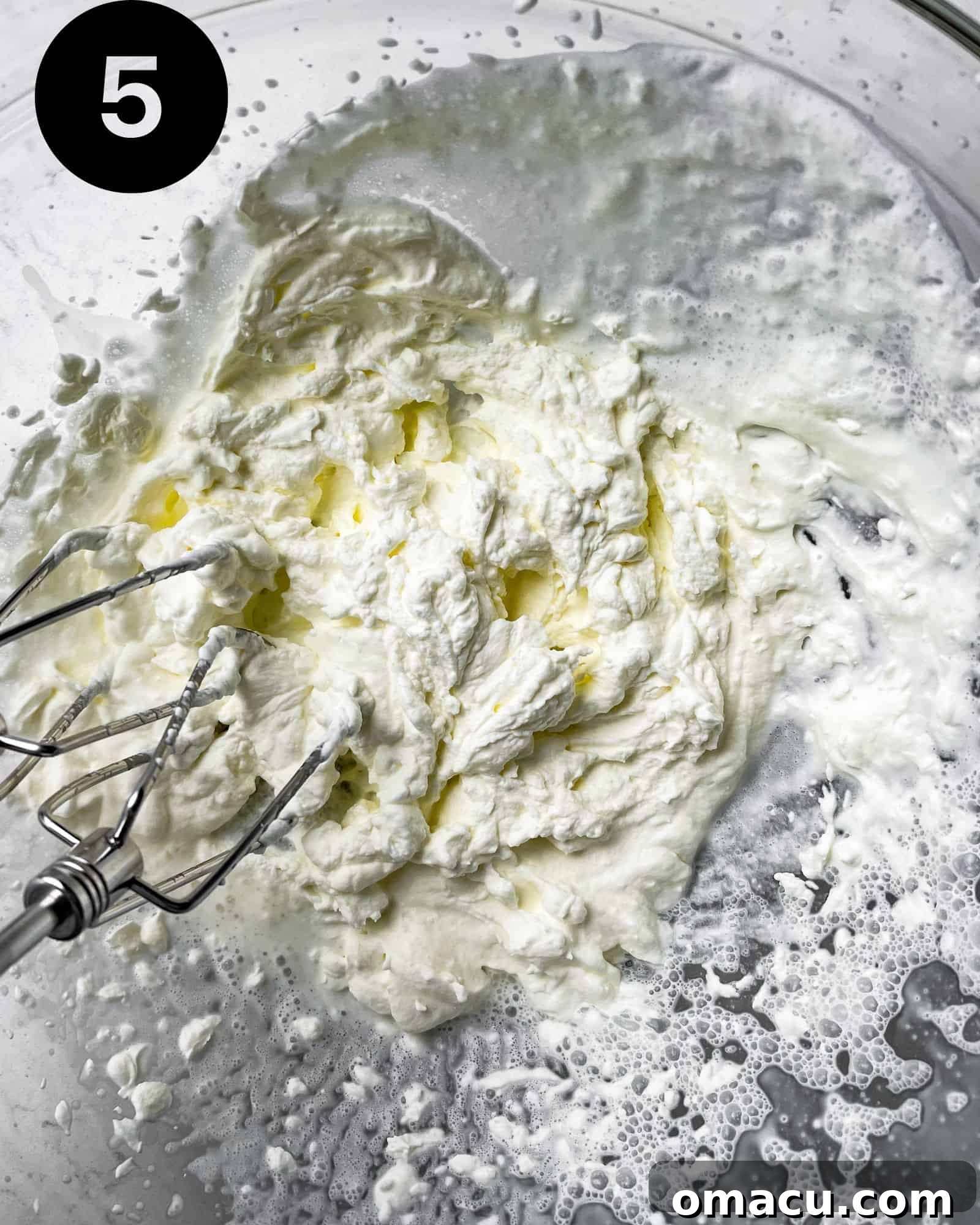 Fluffy whipped cream in a bowl, ready to be folded in.