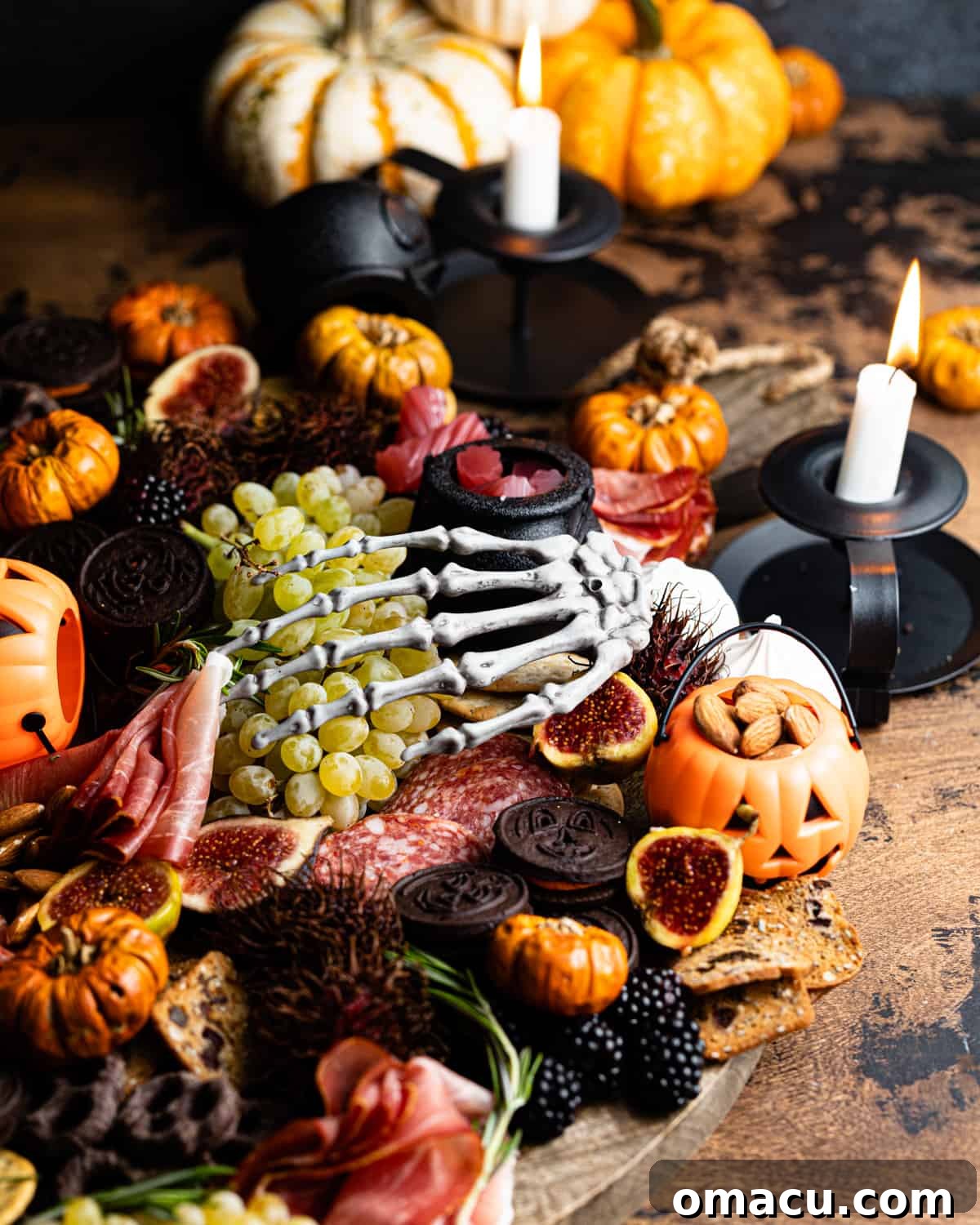 A beautifully arranged Halloween cheese board set on a table, adorned with flickering candles for ambiance.