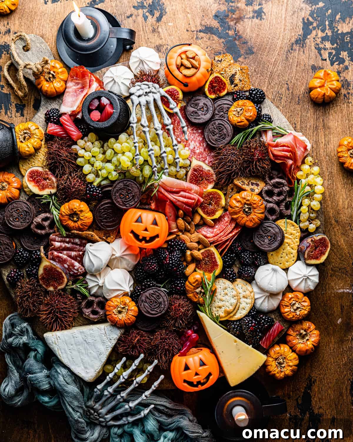 A Halloween charcuterie board on a table, surrounded by charming mini pumpkins and playful skeleton hands.