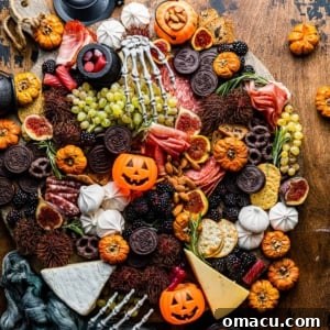 Halloween charcuterie board on a table with mini pumpkins and skeleton hands.