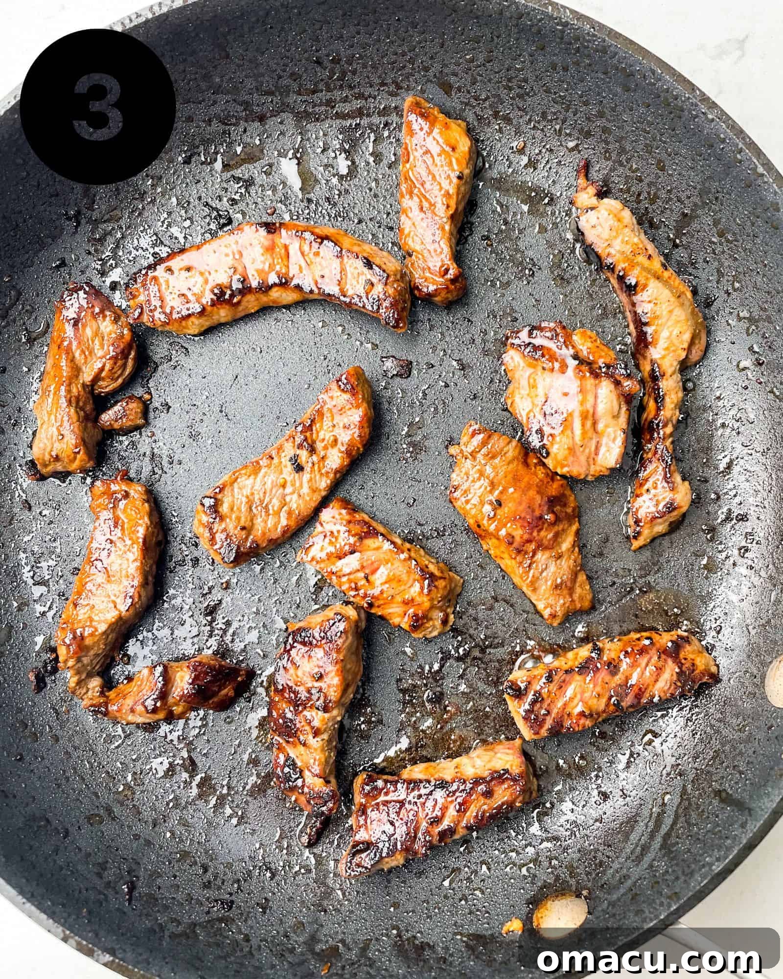 Seared sirloin steak strips in a hot skillet.