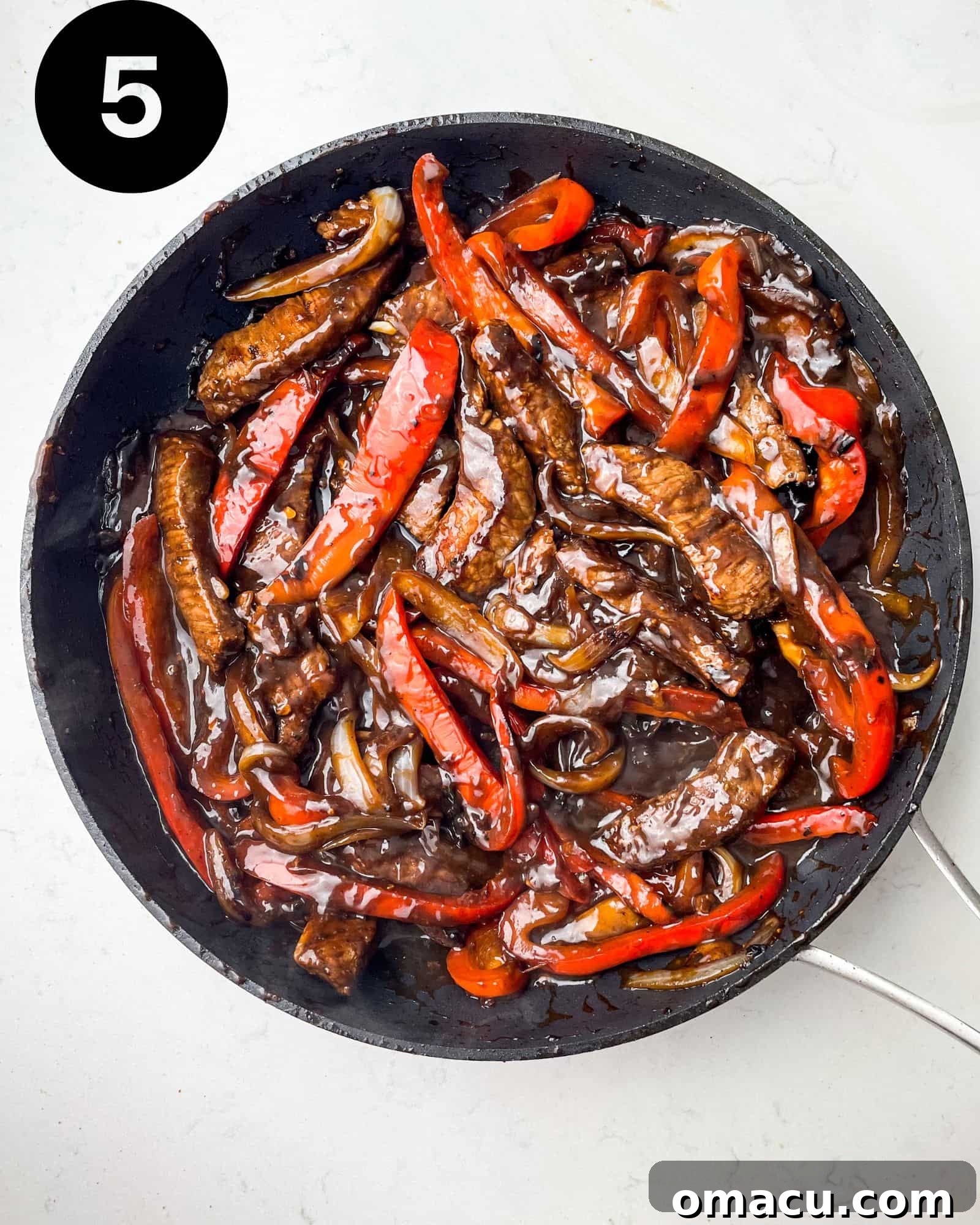 Finished pepper steak dish simmering in a skillet.