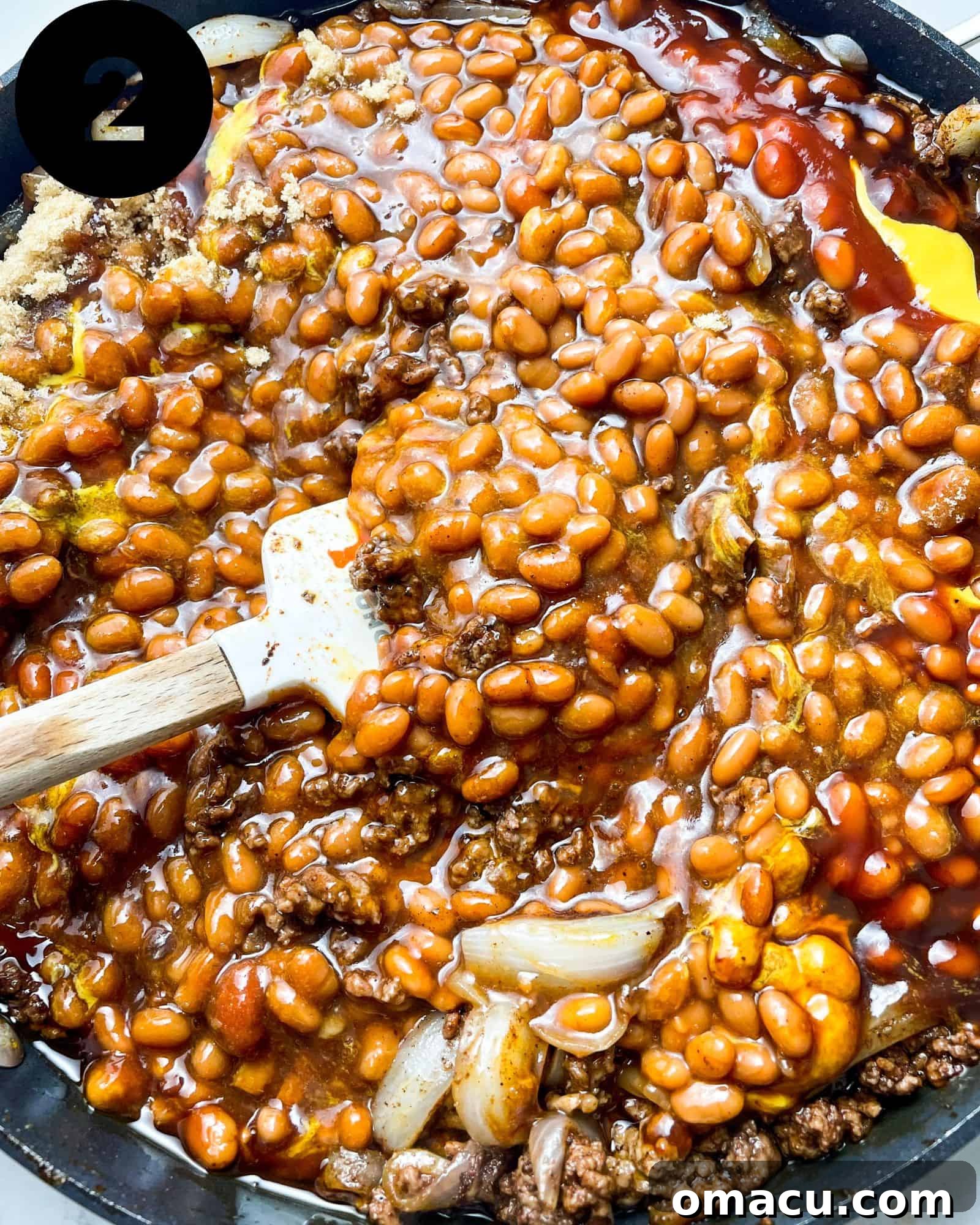 baked beans with ground beef mixed with sauces in a large skillet.