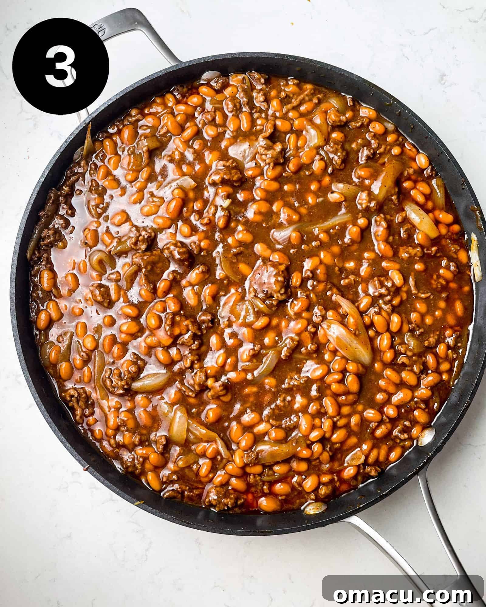 southern baked beans with ground beef fresh out of the oven in a skillet.