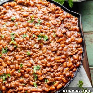 baked beans with ground beef in a skillet topped with sliced green onions, ready to serve.
