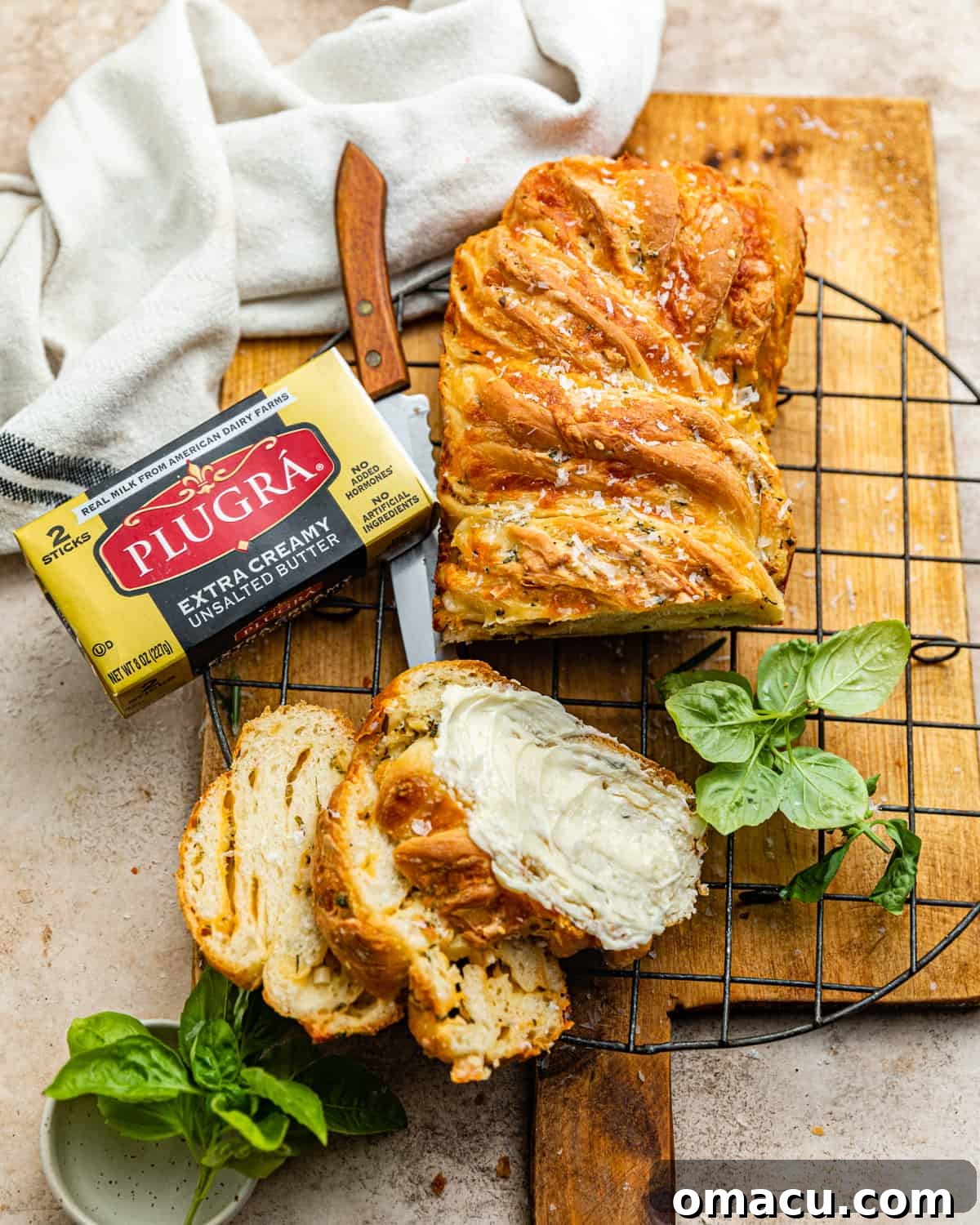 A freshly baked cheese babka cooling on a wire rack, with a patterned kitchen towel nearby.