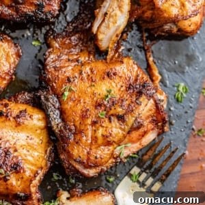 smoked chicken thighs on a plate with a fork and fresh herbs.