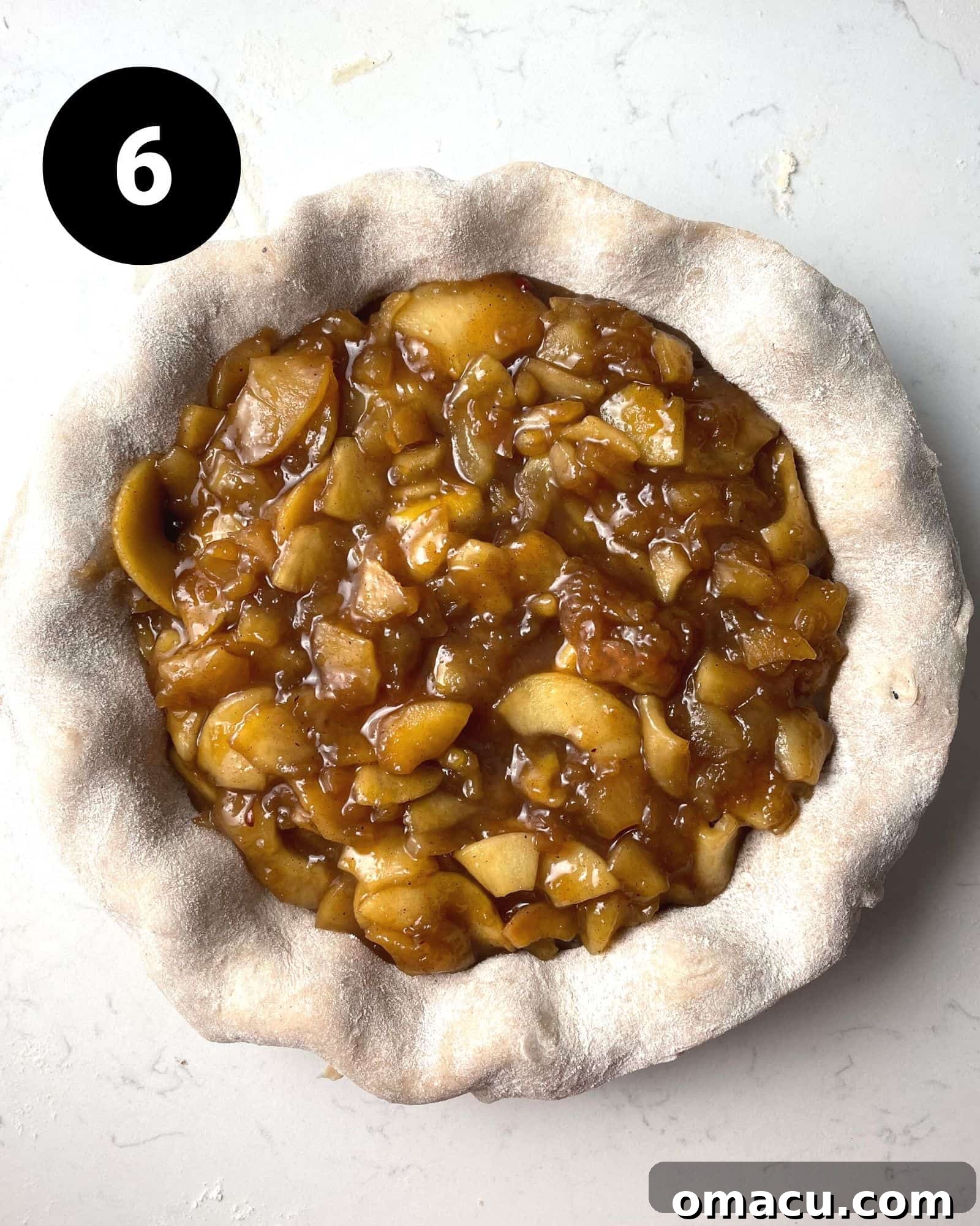 The rich maple apple pie filling nestled perfectly within the bottom pie crust, ready for the top layer.