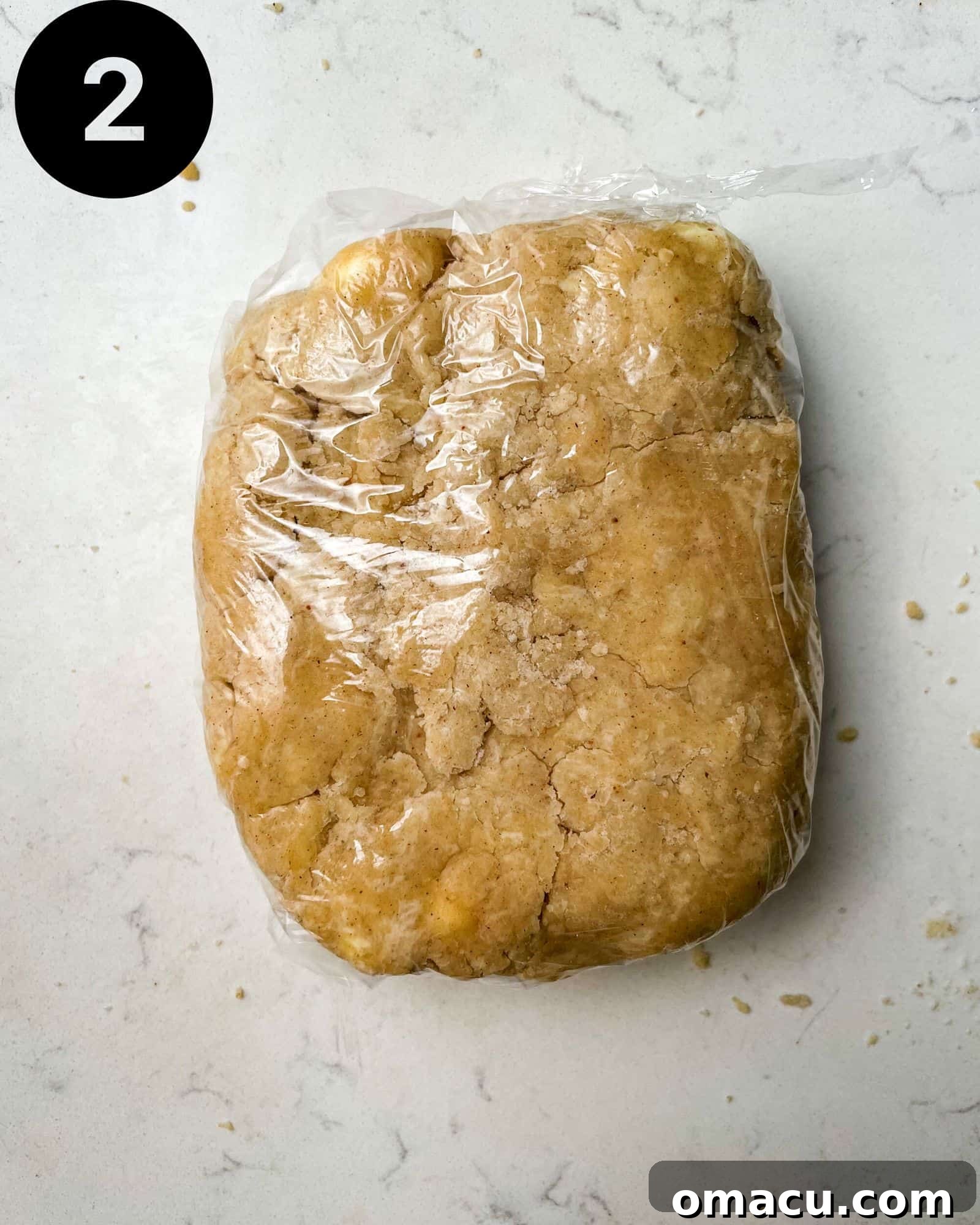 Pie dough wrapped tightly in plastic wrap, chilling in the refrigerator to firm up and relax the gluten before rolling.