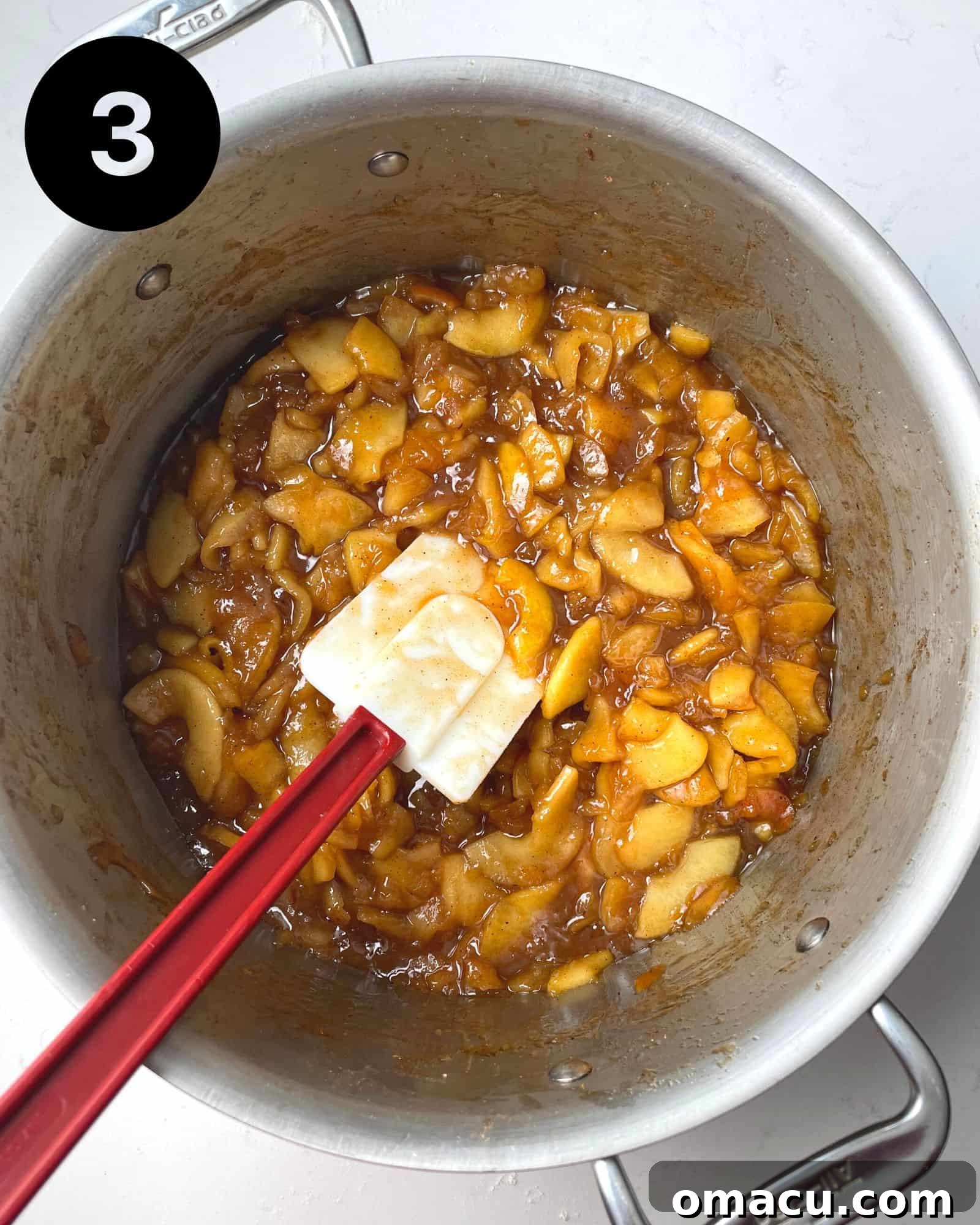 Pre-cooked apple pie filling bubbling gently in a pot, showing its thick, saucy, and caramelized texture.