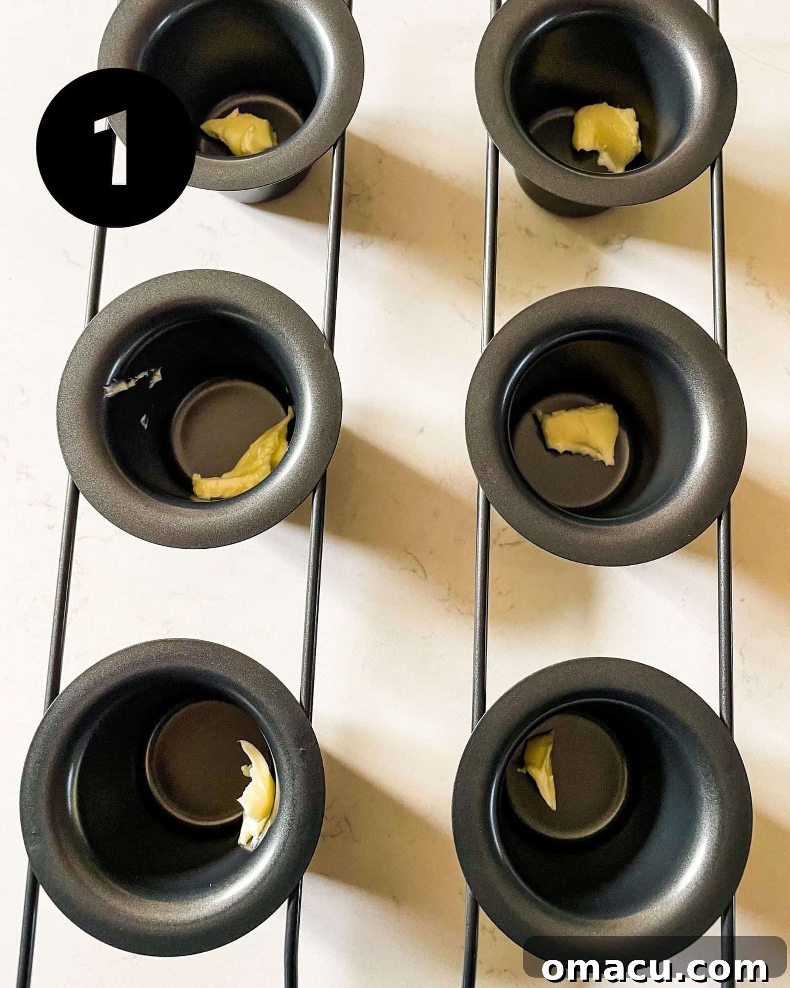 Melted butter sizzling in the cups of a popover pan, preheating in the oven.