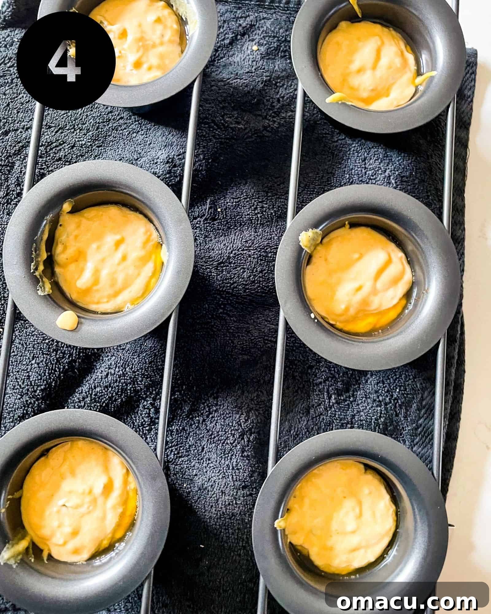 Popover batter poured into the hot, buttered cups of a popover pan, ready for baking.