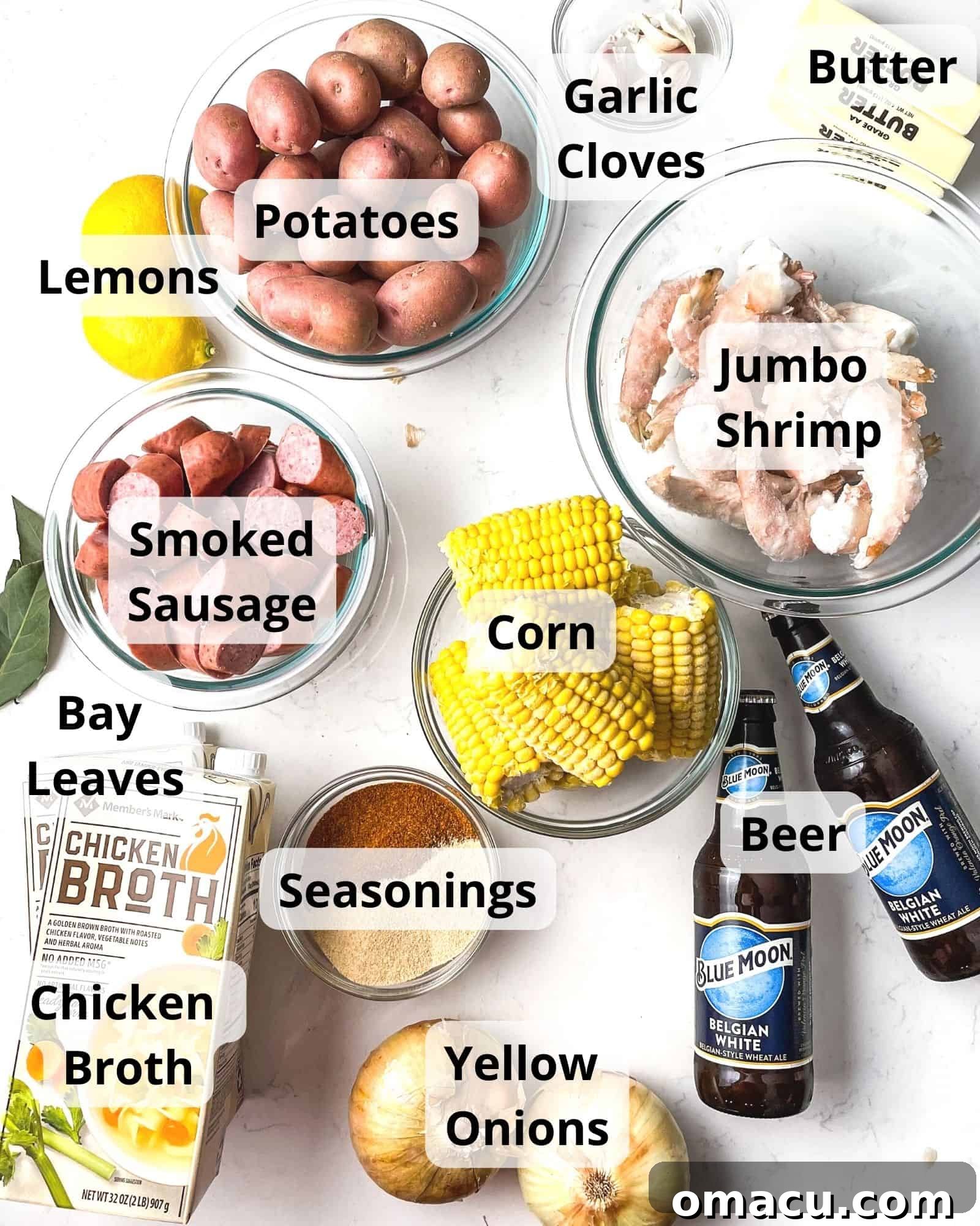 ingredients to make a shrimp boil - jumbo shrimp, corn, beer, chicken broth, bay leaves, old bay, garlic powder, yellow onions, smoked sausage, potatoes, lemons, garlic, and butter.