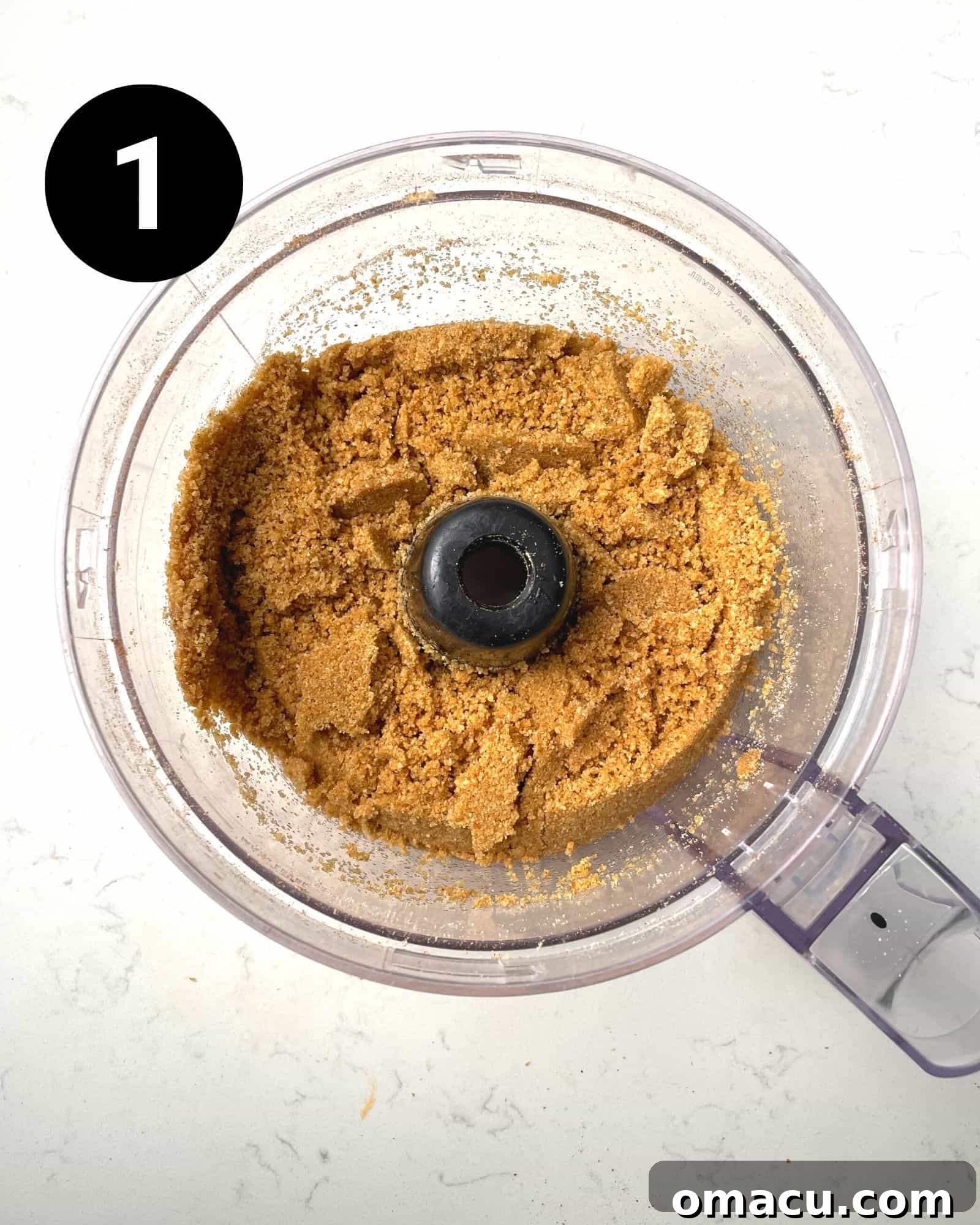 Graham cracker crust mixture in a food processor, showing the crumbly texture.