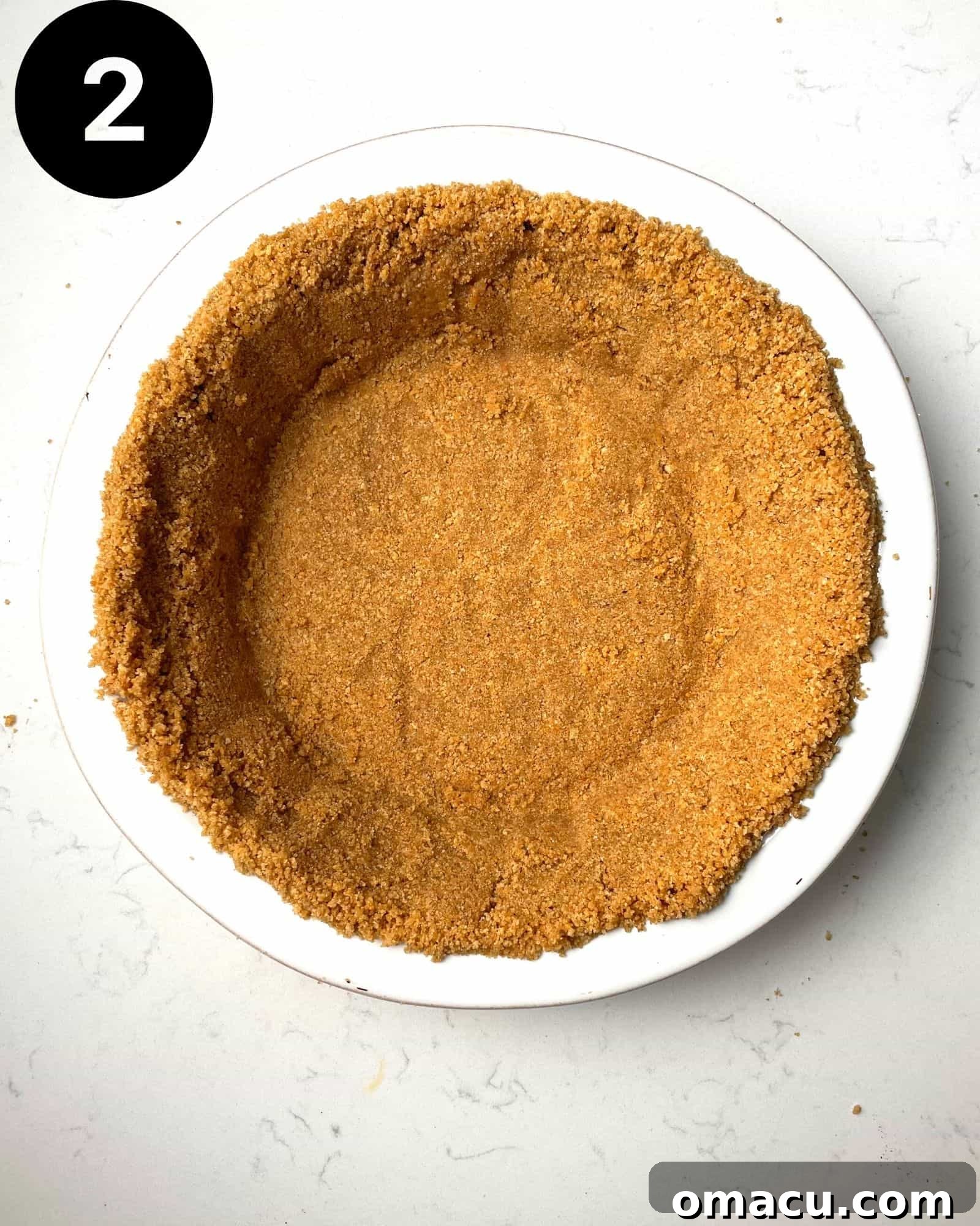 Baked graham cracker crust sitting in a pie dish, golden brown and firm.